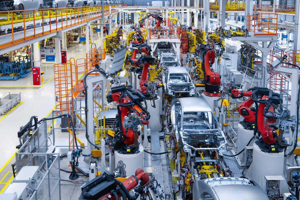 Linha de montagem automatizada com braços robóticos em operação, representando o uso estratégico de energia na indústria automotiva